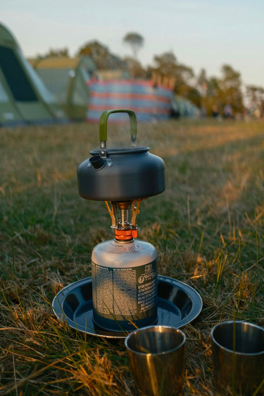 Camping stove with kettle and cups on grass